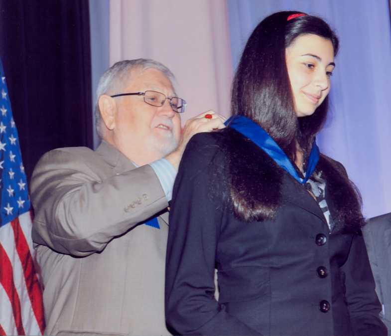 President General Ed Butler presents Kristi with the first place ribbon and medal at the Youth Luncheon.